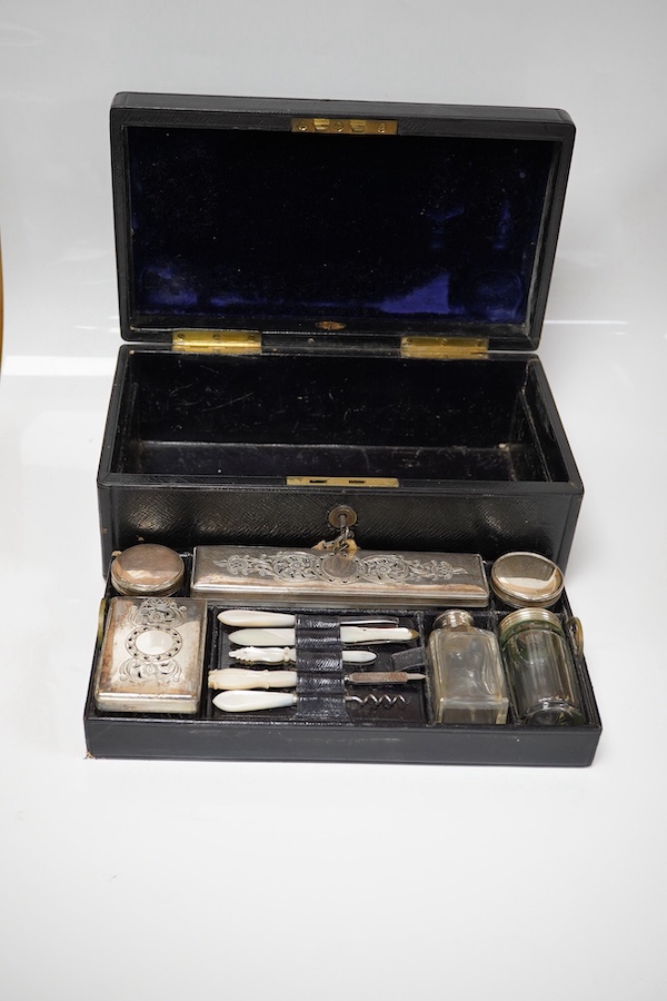 A Victorian leather vanity case with fitted interior to include white metal mounted glass bottles and mother of pearl mounted implements, with key, 27.5cm wide. Condition - fair, handle broken